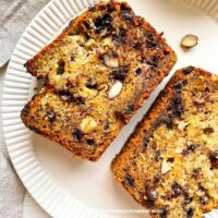 Almond Chocolate Banana Bread: Slices of golden banana bread filled with chocolate chips and sliced almonds, served on a white plate.