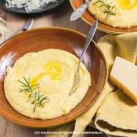 Creamy Parmesan Polenta: Creamy Parmesan polenta topped with melted butter and fresh rosemary, served in a brown bowl.