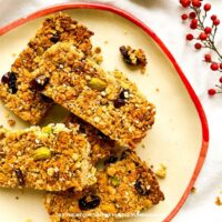 Pistachio Granola Bars: Homemade granola bars with oats, pistachios, dried cranberries, and seeds arranged on a plate.