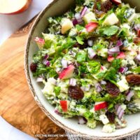Roasted Broccoli Apple Salad: Creamy roasted broccoli and apple salad with red onion, raisins, and fresh herbs served in a bowl.