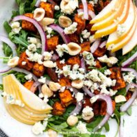 Sweet Potato Pear Salad: Fresh arugula salad with roasted sweet potato, sliced pear, red onion, hazelnuts, and crumbled blue cheese.