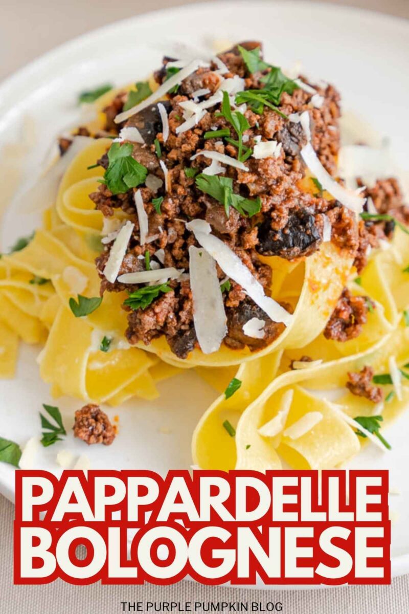 Close-up of pappardelle pasta with rich Bolognese sauce and grated cheese.