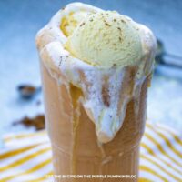 Glass of Pumpkin Milkshake topped with ice cream and overspilling the glass.