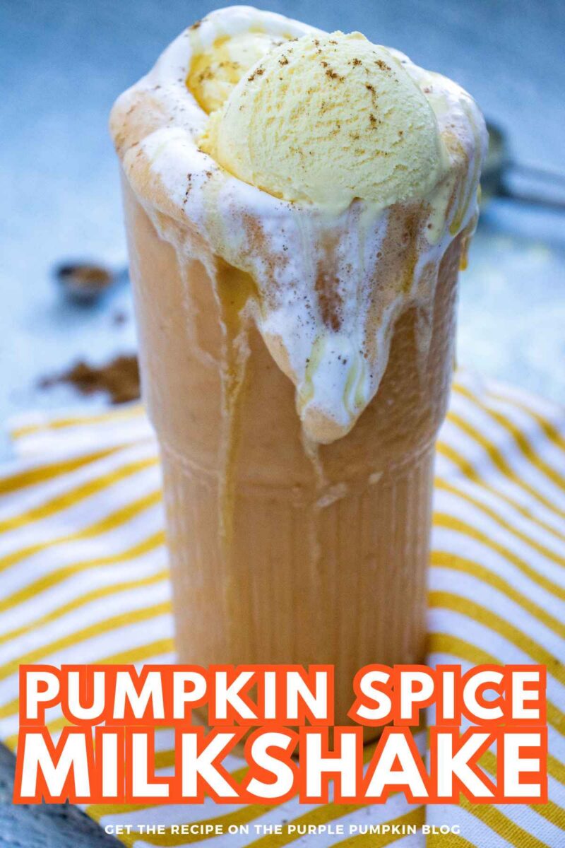 A tall glass of pumpkin spice milkshake topped with whipped cream and a scoop of vanilla ice cream, served on a striped cloth.