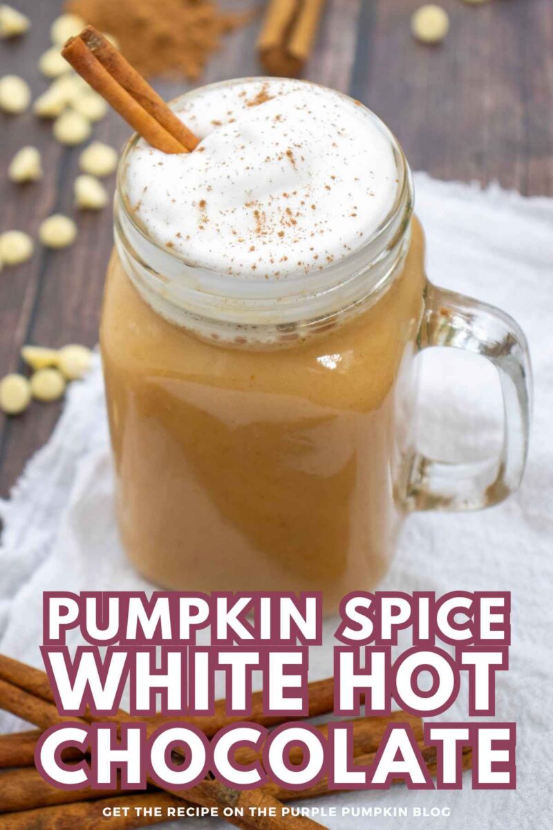 A glass jar filled with creamy pumpkin spice white hot chocolate topped with whipped cream and cinnamon sticks, on a rustic wooden table.